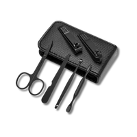 A black manicure set displayed with a textured leather case. The set includes nail clippers, scissors, tweezers, a nail file, and other grooming tools, all in a sleek matte black finish.