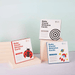 Three packs of "Baby Visual Stimulus Cards" displayed on wooden blocks, with covers showing different designs: one with a black and white concentric circle for ages 0-3 months, another with a red and black ladybug for ages 3-6 months, and the third with a rocket and planet for ages 6-12 months.