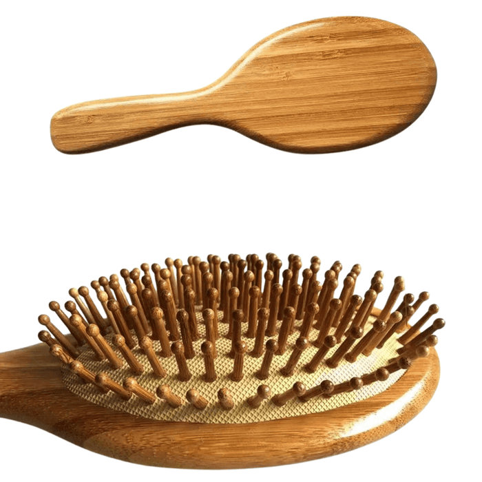 A close-up view of an oval bamboo hairbrush with wooden bristles, focusing on the bristle tips. The back of the brush is shown at the top of the image.