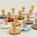 A collection of pacifiers with various pastel-colored bases and bulbous nipples, arranged in multiple rows on a white surface.