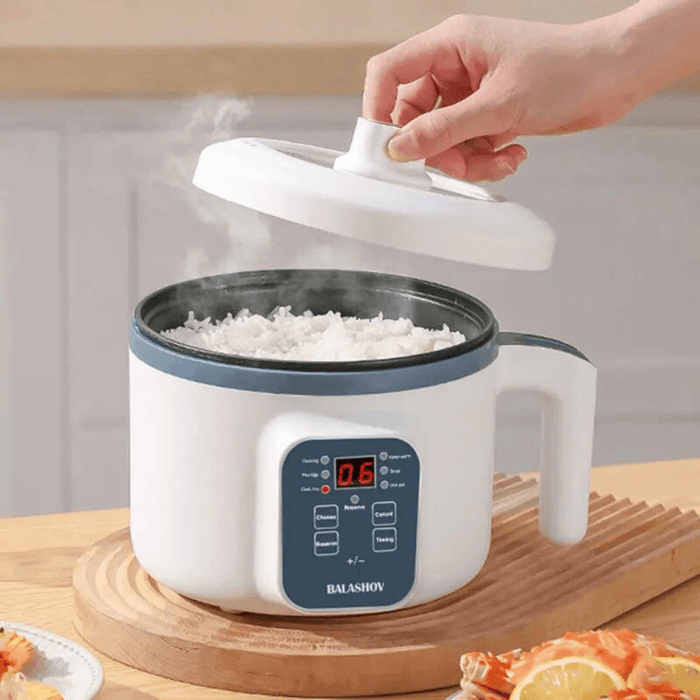 A white multi-functional cooker with digital controls, cooking rice. A hand is lifting the lid off the cooker.