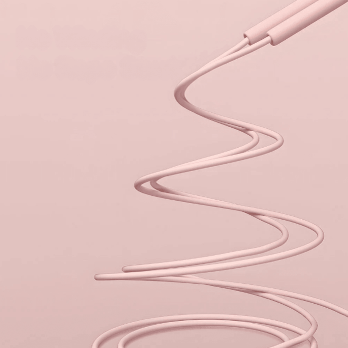 A dynamic image of a pink jump rope captured mid-air, showcasing its flexibility and motion against a pink backdrop. The handles are visible at the top, highlighting their streamlined design.