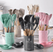 Multiple sets of kitchen utensils in different colors, including turquoise, beige, gray, pink, and white, displayed together on a kitchen counter.