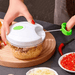 A person using a mini food chopper by pulling its string, with garlic inside the container.