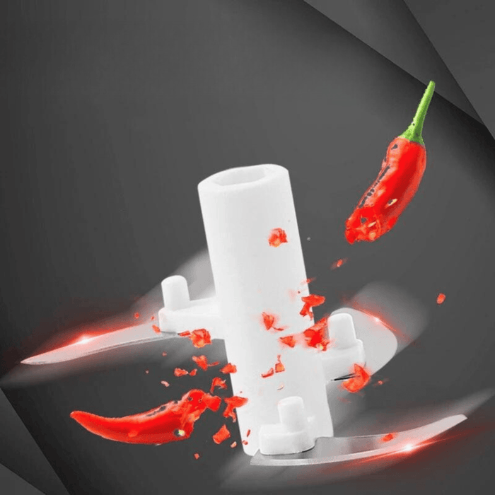 A close-up of a chopping blade with a chili pepper, showing the chopping action.