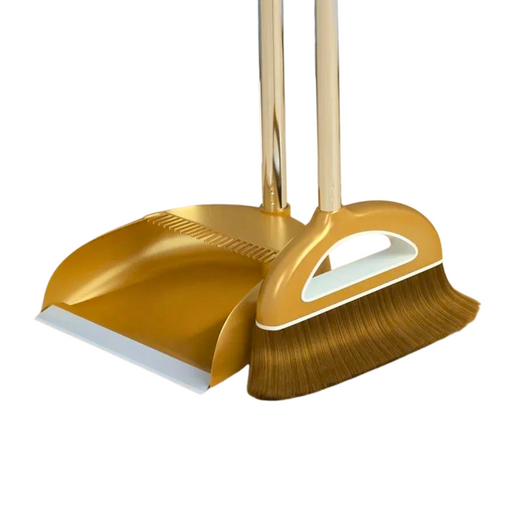 A gold broom and dustpan set with a long handle. The broom has brown or gold bristles, and the dustpan features a comb edge for cleaning the broom's bristles.