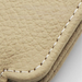 Close-up of a beige, textured leather item with detailed stitching.