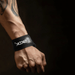 A detailed view of a hand gripping a black, textured strap, highlighting the material and stitching. The background is blurred, focusing attention on the hand and strap.