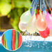 Multiple water balloons in soft pastel shades attached to thin blue nozzles, suspended in mid-air with water droplets visible around them. The inset image features a close-up of variously colored uninflated balloons.