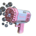 A pink and white rocket-shaped bubble gun releasing multiple bubbles. The gun has multiple nozzles and the word "Rocket" printed on the side.