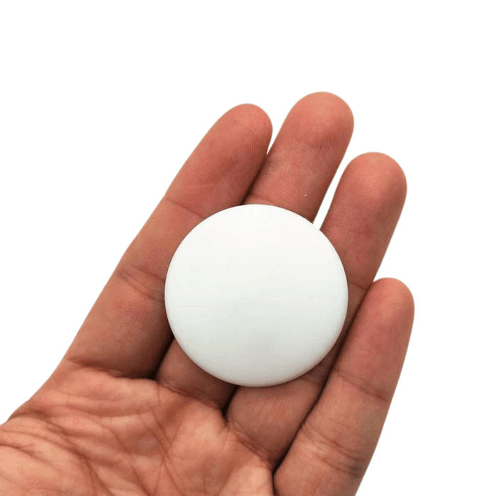 A white silicone protector being held in a hand, showcasing its size and round shape.