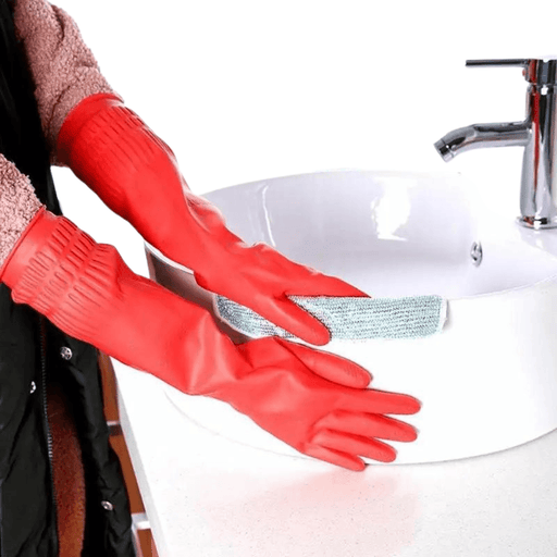 A person wears red cleaning gloves and cleans a white sink. Shown on a white background.