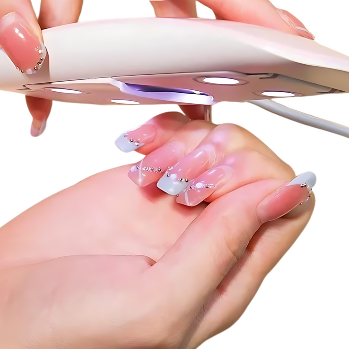 The nail dryer being used on a person's nails. The pink dryer is held above freshly painted nails, with the blue LED light shining down to cure the polish.