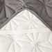 Close-up of the underside of the gray quilted mattress cover pad showing the white side with elastic bands for securing the pad to the mattress.