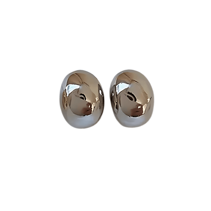 a pair of small, oval-shaped silver stud earrings. They have a smooth, highly reflective surface, giving them a sleek and modern appearance. The earrings are displayed against a plain white background.