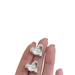 a pair of silver heart-shaped stud earrings being held in a hand. The earrings have a textured surface, and the photo highlights the detailed craftsmanship.