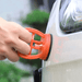 A close-up of a person’s hand attaching an orange suction cup to the curved surface of a car’s body, possibly for the purpose of dent removal or similar repair work.