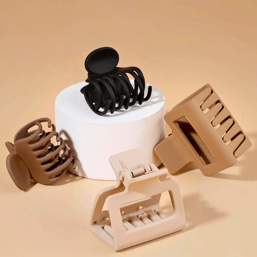 An array of hair clips displayed on a cylindrical stand with brown background. The collection includes clips in various designs and neutral colors such as black, brown, and beige. These accessories vary from more traditional claw clips to modern designs with mechanical features, offering options for different hair types and preferences.