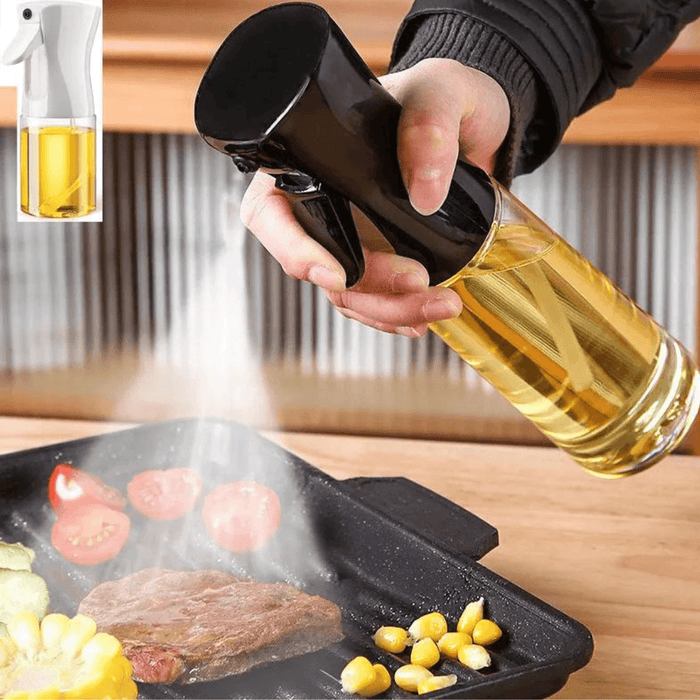 A hand using a black oil spray bottle to spray oil onto food in a pan.