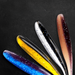 A close-up view of five soft plastic fishing lures, fanned out on a dark background, featuring different color patterns, including blue, yellow, white, and brown, with speckled designs.