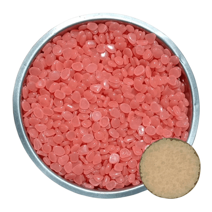 A metal bowl filled with orange-pink pebbles. A small inset shows the pebbles glowing light yellow in the dark