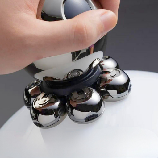  A close-up of a hand holding the trimmer, emphasizing the grip and the design of the rotating blades on the head. The trimmer is in use, demonstrating its ergonomic design.