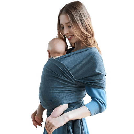 A young woman, smiling gently, cradles an infant wrapped snugly in a soft, blue-gray baby sling. The setting focuses solely on the intimate and tender moment between mother and child, emphasizing the comfort and bond facilitated by the use of the baby wrap.