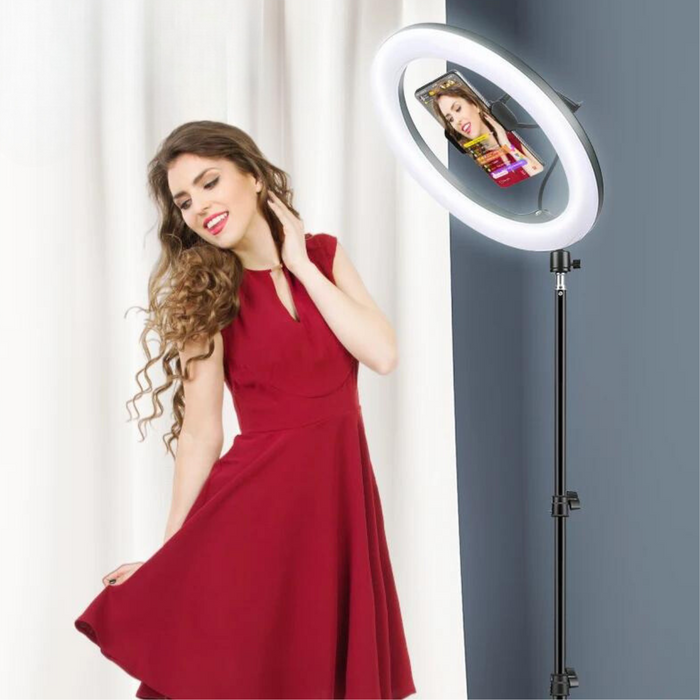  the ring light in use, with a woman posing in front of it. The ring light illuminates her evenly, and the smartphone attachment is visible in the center, demonstrating the practical application of the setup for portrait or video shooting.