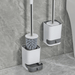 A close-up of a toilet brush set with stainless steel handle and a detachable holder, showing its placement on the bathroom floor.