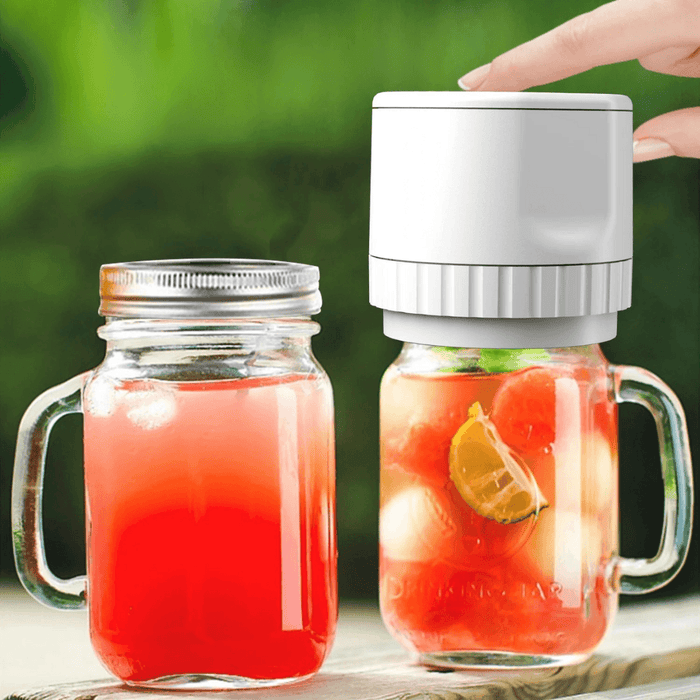 A white electric vacuum sealer in use on a mason jar filled with a refreshing red beverage.