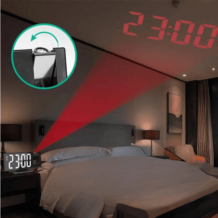 A digital alarm clock with a projector displaying the time 23:00 in red digits on a bedroom wall, with an inset showing a close-up of the projector, displayed on a dark bedroom background.