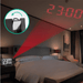 A digital alarm clock with a projector displaying the time 23:00 in red digits on a bedroom wall, with an inset showing a close-up of the projector, displayed on a dark bedroom background.