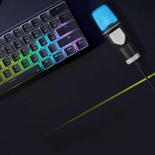 USB microphone placed beside a keyboard with RGB backlighting. The microphone glows blue, emphasizing its aesthetic appeal and compatibility with gaming or streaming setups.