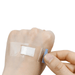 A close-up showing a transparent adhesive bandage applied to the back of a hand, highlighting the bandage's discreet and barely noticeable presence on the skin. This image emphasizes the bandage’s clear material, which makes it less visible when worn.