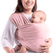 A joyful mother smiles warmly as she holds her baby in a soft, pink wrap sling. The sling envelops the baby securely, promoting a snug and intimate bond between mother and child. The mother's attire, a light patterned top, adds a gentle touch to the tender moment. This setup not only provides comfort and security to the baby but also allows the mother to maintain closeness as she engages in daily activities, demonstrating the functional and emotional benefits of wrap slings.