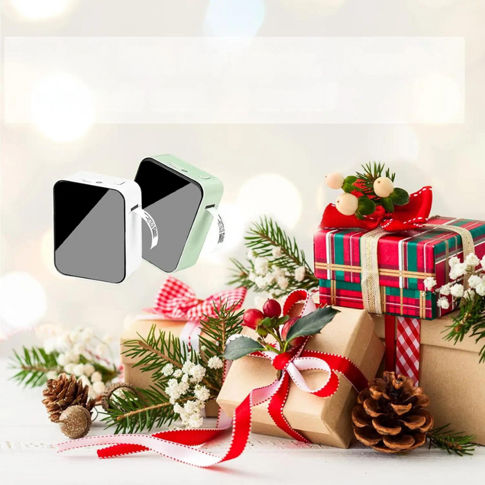 Two mini Bluetooth thermal label printers, one white and one green, placed among holiday decorations including gift boxes, pinecones, and festive ribbons.