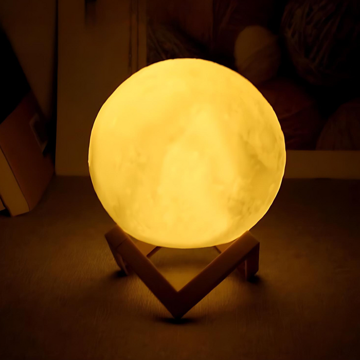 A yellow moon lamp is illuminated, placed on a wooden stand. The background is dim, highlighting the soft glow of the lamp.