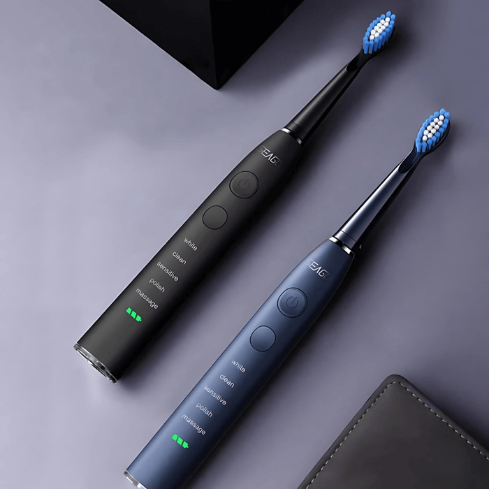 Two electric toothbrushes, one in black and the other in dark blue, side by side against a dark background. Both display their mode options and battery levels, with settings including "white", "clean", "sensitive", "polish", and "massage".