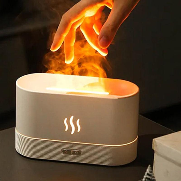 A white aroma diffuser with orange flame-like mist. A hand is shown above the diffuser, interacting with the mist. The diffuser has a control panel with two buttons.