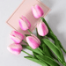 A bouquet of baby pink tulips with green leaves.