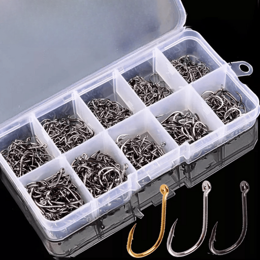 A plastic storage box containing various sizes of fishing hooks, neatly organized in separate compartments. Three individual hooks, in gold, black, and silver colors, are displayed in front of the box on a reflective surface.