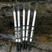 A set of five white telescopic fishing rods standing upright, possibly by a stream or river. The rods are fully extended, showing their sleek design and compact handles, perfect for outdoor fishing adventures.