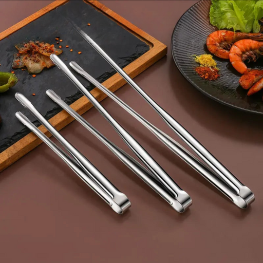 stainless steel tongs laid out on a surface, with some food items nearby, showcasing their versatility in the kitchen.