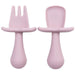 A close-up shot of two light pink silicone baby utensils, a fork and a spoon, showing their detailed design and texture.