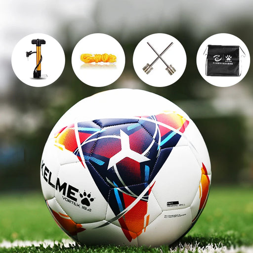 White Kelme Vortex soccer ball on grass, with pump, needle, and bag.