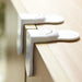 Close-up of two white safety locks attached to the top edge of a wooden cabinet door, designed to prevent the door from being opened by small children.