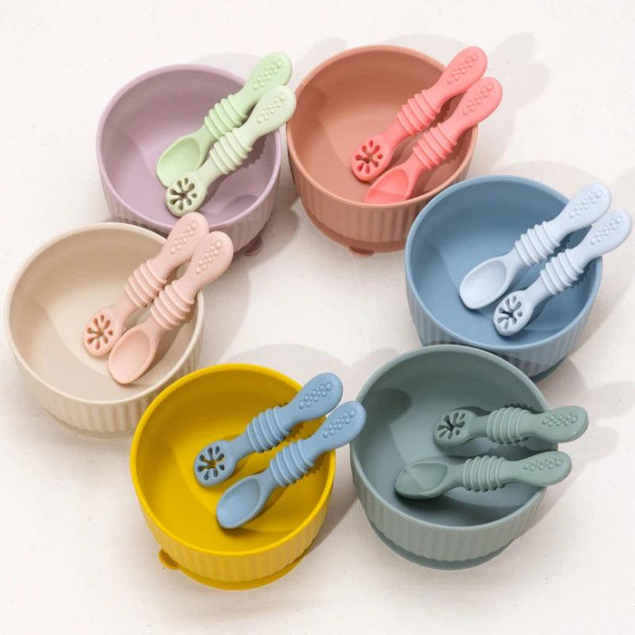 Several colorful baby bowls each with a matching spoon placed inside, arranged in a circle on a white background.