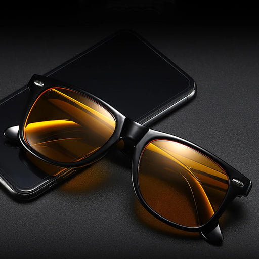 Black-framed sunglasses with orange-tinted lenses placed on top of a smartphone.