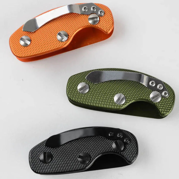 Three small, rectangular key organizers made from textured metal in orange, green, and black, each featuring a sleek silver clip attached to the top.