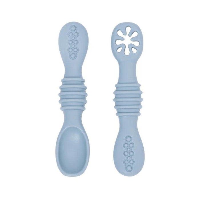 A close-up of two blue baby spoons, one with a regular spoon shape and the other with a cut-out flower design, against a white background.